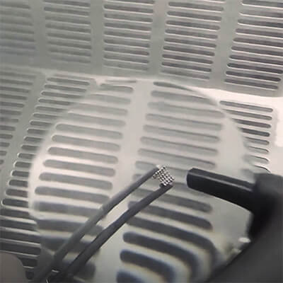 An orthodontic bracket being sandblasted under the 6x bifocal of a Perfect View Magnifier.