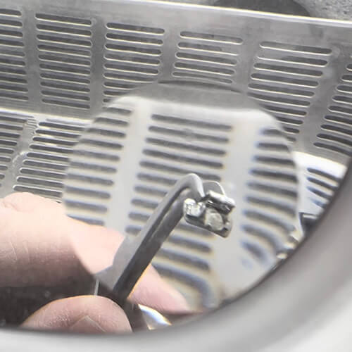 An orthodontic bracket under the 6x bifocal of a Perfect View Magnifier.
